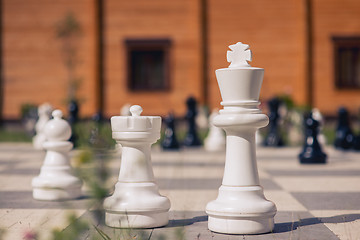 Image showing big chess on a background of  wooden house and grass field