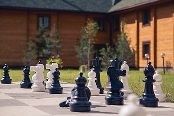 Image showing big chess on a background of  wooden house and grass field