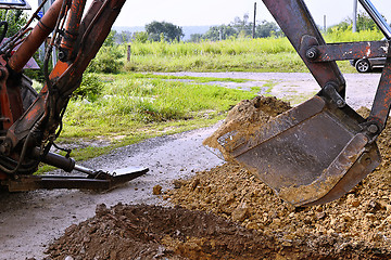 Image showing Excavator bucket digging a trench in the dirt ground