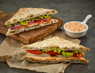 Image showing various sandwiches on paper and wooden cutting board