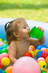 Image showing The little baby girl playing with toys in inflatable pool in the summer sunny day