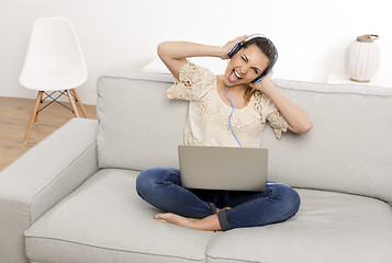 Image showing Listen music on her laptop