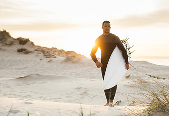 Image showing A surfer with his surfboard 