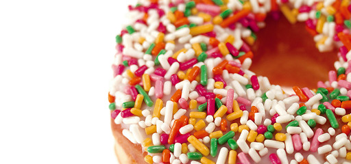 Image showing Pink Iced Doughnut covered in sprinkles isolated