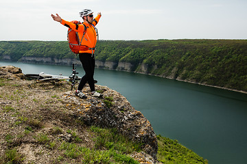 Image showing Cyclist in Orange Wear Riding the Bike above River