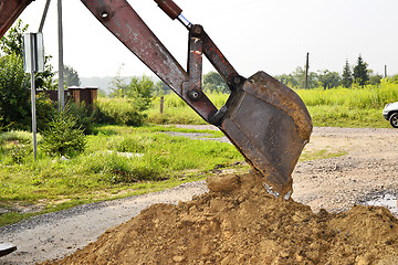 Image showing Excavator bucket digging a trench in the dirt ground