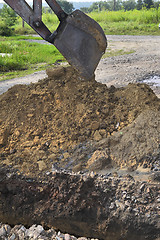 Image showing Excavator bucket digging a trench in the dirt ground