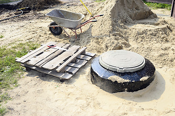 Image showing Construction site with new armed manholes, cart, sand and equipm