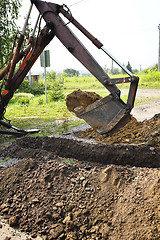 Image showing Excavator bucket digging a trench in the dirt ground