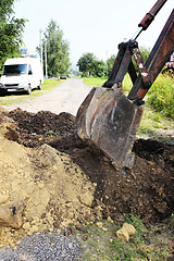 Image showing Excavator bucket digging a trench in the dirt ground