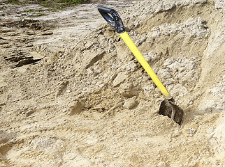 Image showing Yellow shovel stands in a pile of building sand