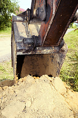 Image showing Excavator bucket digging a trench in the dirt ground