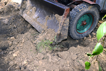 Image showing Excavator bucket digging a trench in the dirt ground