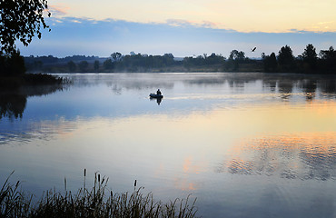 Image showing A fisherman in a boat sailing in the morning mist