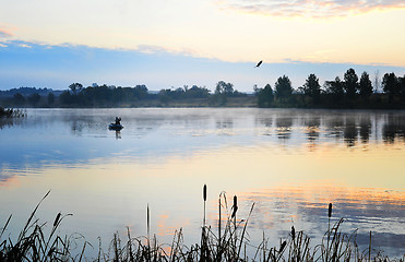 Image showing A fisherman in a boat sailing in the morning mist