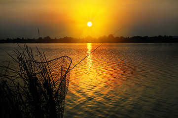 Image showing Fishing rod and tank against the sunset on the lake fishing