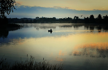 Image showing A fisherman in a boat sailing in the morning mist