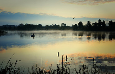 Image showing A fisherman in a boat sailing in the morning mist