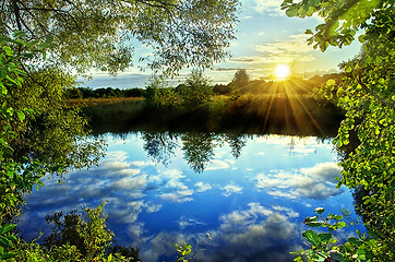 Image showing Sunrise over the river in the summer with reflection of clouds i