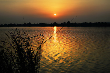 Image showing Fishing rod and tank against the sunset on the lake fishing