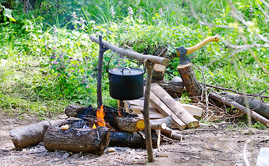 Image showing Tourist pot of water hanging over a fire of wood in the Camping