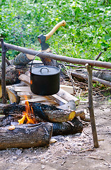 Image showing Tourist pot of water hanging over a fire of wood in the Camping