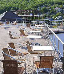 Image showing Wicker chairs with metal legs and racks are in an open cafe area