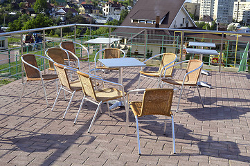 Image showing Wicker chairs with metal legs and racks are in an open cafe area