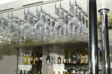 Image showing A number of washed glasses hung to dry in the bar
