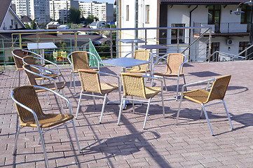 Image showing Wicker chairs with metal legs and racks are in an open cafe area