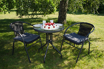 Image showing Table with strawberry cake in a garden