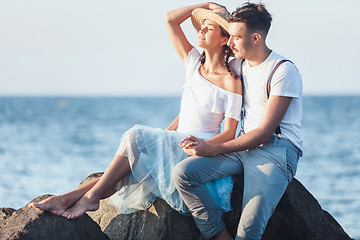 Image showing Happy young romantic couple relaxing on the beach and watching the sunset