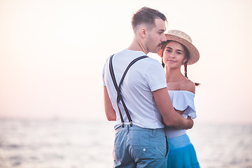 Image showing Happy young romantic couple relaxing on the beach and watching the sunset