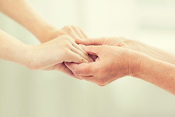 Image showing close up of senior and young woman holding hands