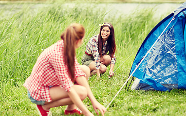 Image showing smiling friends setting up tent outdoors