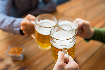 Image showing close up of hands with beer mugs at bar or pub