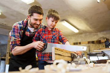 Image showing father and son with saw working at workshop