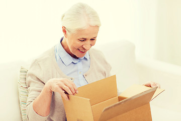 Image showing happy senior woman with parcel box at home