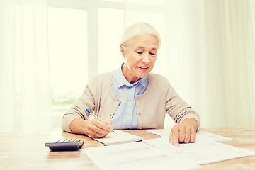 Image showing senior woman with papers and calculator at home