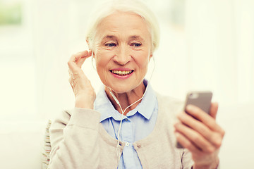 Image showing senior woman with smartphone and earphones at home