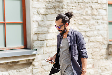 Image showing man with earphones and smartphone walking in city