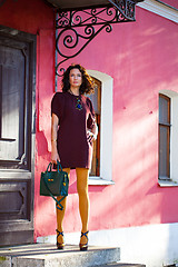 Image showing pretty woman in a burgundy dress with a green handbag