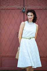 Image showing woman in a white dress near the old metal gate