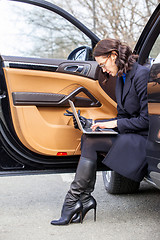 Image showing Work on the road. woman in a dark coat with a laptop