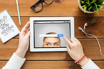 Image showing close up of woman with tablet pc on wooden table