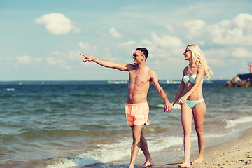 Image showing happy couple in swimwear walking on summer beach