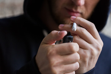 Image showing close up of addict lighting up marijuana joint