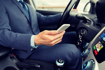 Image showing close up of man with smartphone driving car