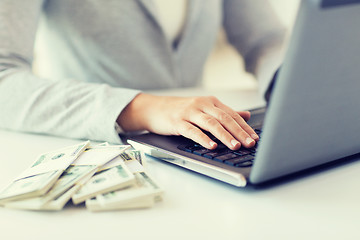 Image showing close up of woman hands with laptop and money