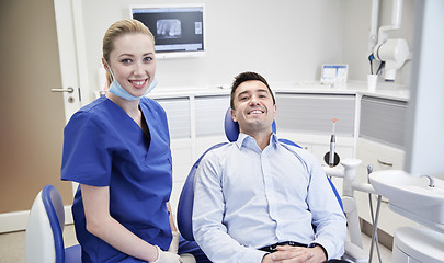 Image showing happy female dentist with man patient at clinic